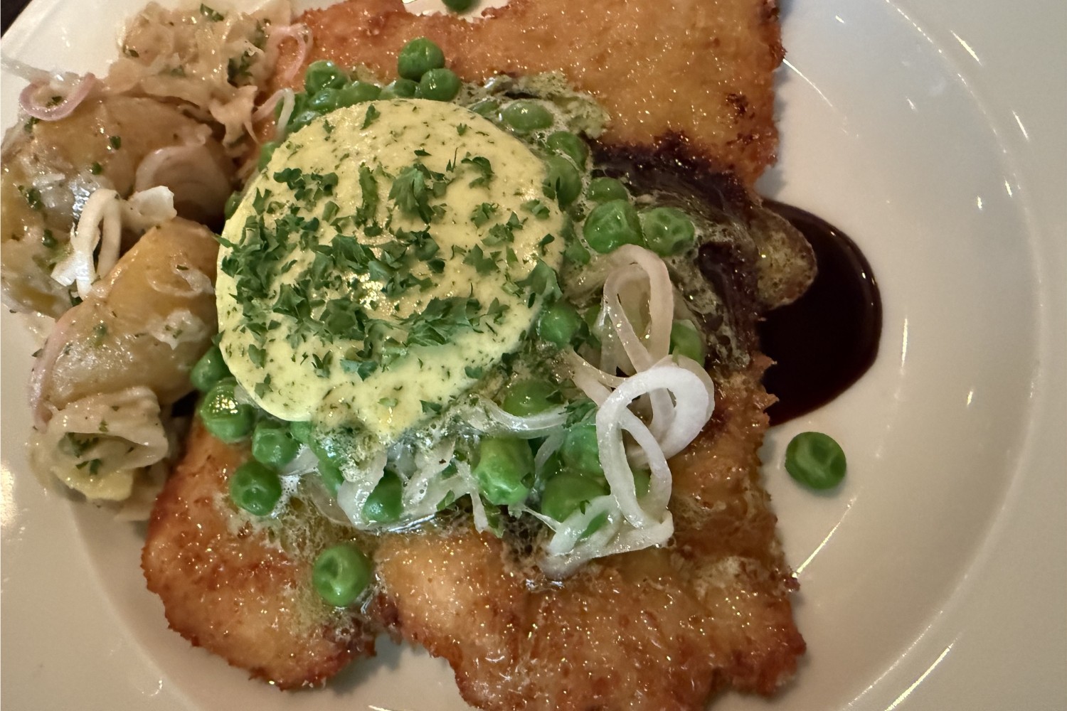 Schnitzel med surkålspotatis, persiljesmör och gröna ärtor